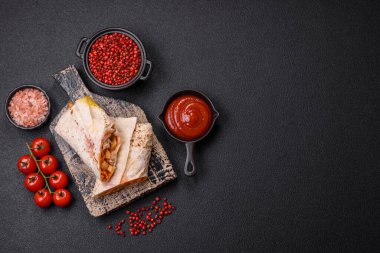 Lezzetli sulu rulo ya da tavuklu shawarma, domates, salata ve soslu koyu beton arka planda