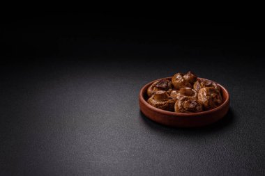 Izgarada pişirilmiş lezzetli sulu şampiyonlar koyu beton arka planda seramik tabakta tuz ve baharatlarla.