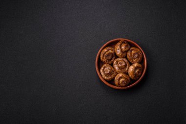 Izgarada pişirilmiş lezzetli sulu şampiyonlar koyu beton arka planda seramik tabakta tuz ve baharatlarla.