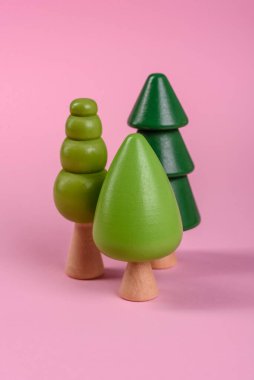 Pembe arka planda yeşil taç ve gövdesi olan bir ağacın ahşap modeli. Ahşap oyuncaklarla çocuk büyümesi