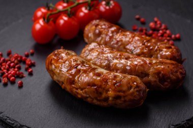 Koyu beton arka planda tuzlu, baharatlı ve otlu kızarmış domuz veya tavuk sosisi.