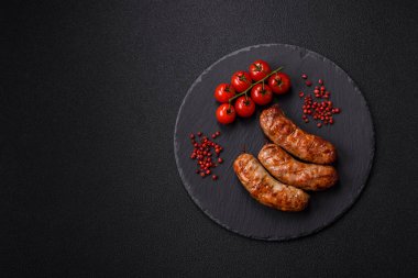 Koyu beton arka planda tuzlu, baharatlı ve otlu kızarmış domuz veya tavuk sosisi.