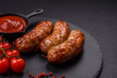 Koyu beton arka planda tuzlu, baharatlı ve otlu kızarmış domuz veya tavuk sosisi.