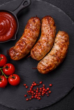 Koyu beton arka planda tuzlu, baharatlı ve otlu kızarmış domuz veya tavuk sosisi.