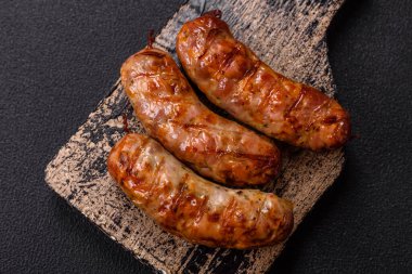 Koyu beton arka planda tuzlu, baharatlı ve otlu kızarmış domuz veya tavuk sosisi.