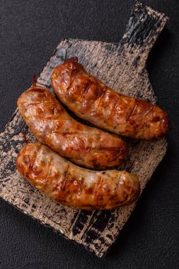 Koyu beton arka planda tuzlu, baharatlı ve otlu kızarmış domuz veya tavuk sosisi.