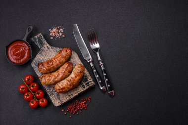 Koyu beton arka planda tuzlu, baharatlı ve otlu kızarmış domuz veya tavuk sosisi.