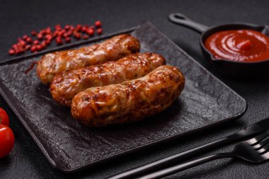 Koyu beton arka planda tuzlu, baharatlı ve otlu kızarmış domuz veya tavuk sosisi.