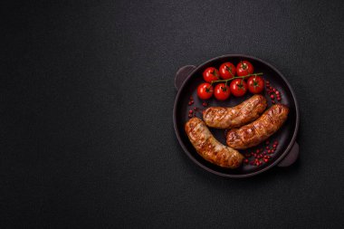 Koyu beton arka planda tuzlu, baharatlı ve otlu kızarmış domuz veya tavuk sosisi.