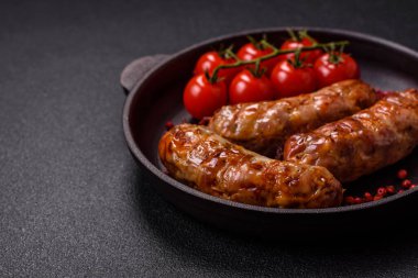 Koyu beton arka planda tuzlu, baharatlı ve otlu kızarmış domuz veya tavuk sosisi.