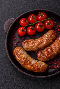 Koyu beton arka planda tuzlu, baharatlı ve otlu kızarmış domuz veya tavuk sosisi.