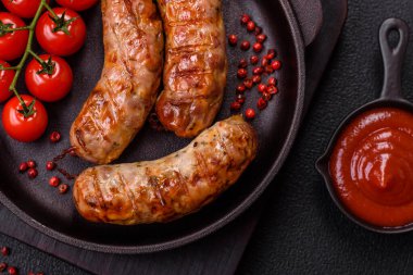 Koyu beton arka planda tuzlu, baharatlı ve otlu kızarmış domuz veya tavuk sosisi.