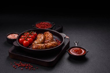 Koyu beton arka planda tuzlu, baharatlı ve otlu kızarmış domuz veya tavuk sosisi.