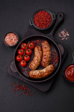 Koyu beton arka planda tuzlu, baharatlı ve otlu kızarmış domuz veya tavuk sosisi.