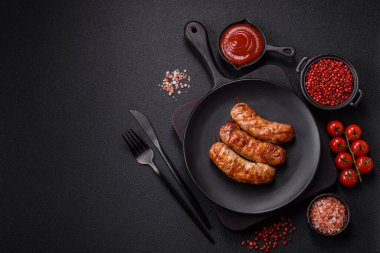 Koyu beton arka planda tuzlu, baharatlı ve otlu kızarmış domuz veya tavuk sosisi.