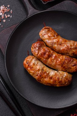 Koyu beton arka planda tuzlu, baharatlı ve otlu kızarmış domuz veya tavuk sosisi.