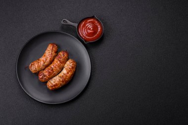 Koyu beton arka planda tuzlu, baharatlı ve otlu kızarmış domuz veya tavuk sosisi.