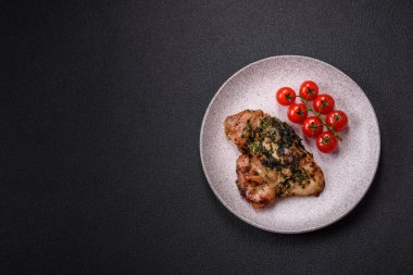 Koyu beton bir arka planda tuzlu, baharatlı ve otlu ızgara kemiksiz tavuk budu.