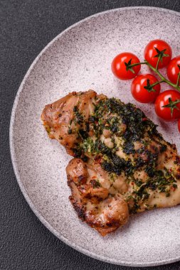 Koyu beton bir arka planda tuzlu, baharatlı ve otlu ızgara kemiksiz tavuk budu.