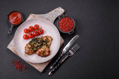 Koyu beton bir arka planda tuzlu, baharatlı ve otlu ızgara kemiksiz tavuk budu.