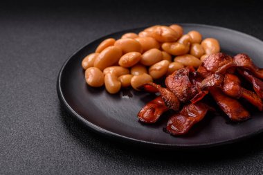 Tuz ve baharatla dilimlenmiş kızarmış sosisler koyu beton arka planda İngiliz kahvaltısı için bir malzeme.