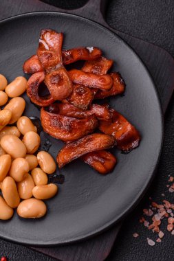 Tuz ve baharatla dilimlenmiş kızarmış sosisler koyu beton arka planda İngiliz kahvaltısı için bir malzeme.