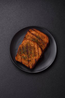 Lezzetli çıtır kıtır ekmek ya da esmer ekmekten yapılmış sarımsak soslu bruschetta ve koyu beton arka planda otlar.