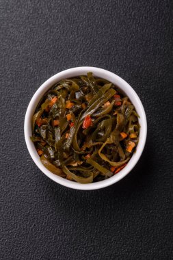 Koyu beton arka planda kırmızı biber, baharat ve tuz ile marine edilmiş lezzetli deniz yosunu. Lezzetli vejetaryen salatası