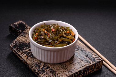 Koyu beton arka planda kırmızı biber, baharat ve tuz ile marine edilmiş lezzetli deniz yosunu. Lezzetli vejetaryen salatası