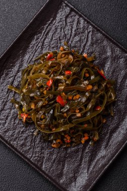 Koyu beton arka planda kırmızı biber, baharat ve tuz ile marine edilmiş lezzetli deniz yosunu. Lezzetli vejetaryen salatası