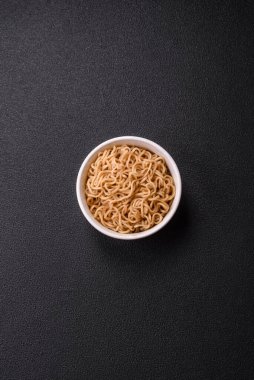 Koyu beton zemin üzerinde tuz ve baharatlı Asya usulü pirinç eriştesi.