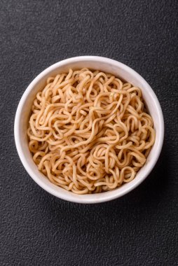 Koyu beton zemin üzerinde tuz ve baharatlı Asya usulü pirinç eriştesi.