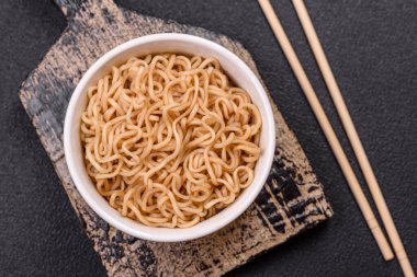 Koyu beton zemin üzerinde tuz ve baharatlı Asya usulü pirinç eriştesi.