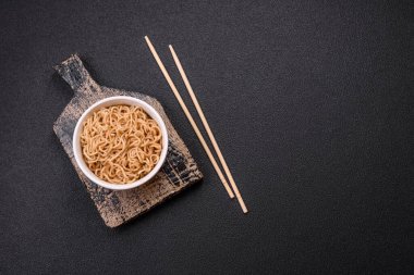 Koyu beton zemin üzerinde tuz ve baharatlı Asya usulü pirinç eriştesi.