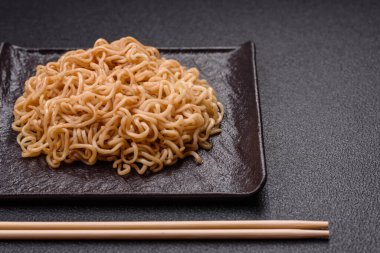 Koyu beton zemin üzerinde tuz ve baharatlı Asya usulü pirinç eriştesi.