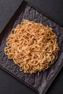 Koyu beton zemin üzerinde tuz ve baharatlı Asya usulü pirinç eriştesi.