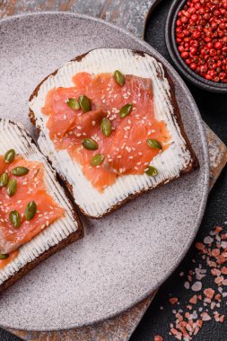 Tost, somon, krem peynir, kabak tohumu ve susam tohumlu sandviç veya bruschetta.