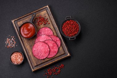 Lezzetli füme salam. Tuz, baharat ve otlarla dilimlenmiş. Koyu beton bir arka planda.