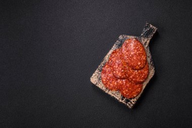 Lezzetli tütsülenmiş sucuklu sosis. Tuz, baharat ve otlarla dilimlenmiş. Koyu beton arka planda.