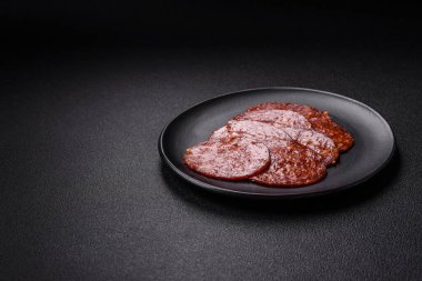 Lezzetli tütsülenmiş sucuklu sosis. Tuz, baharat ve otlarla dilimlenmiş. Koyu beton arka planda.