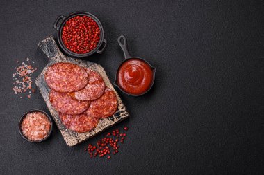 Lezzetli tütsülenmiş sucuklu sosis. Tuz, baharat ve otlarla dilimlenmiş. Koyu beton arka planda.