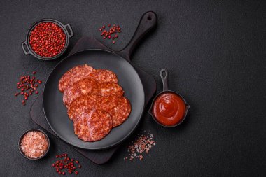 Lezzetli tütsülenmiş sucuklu sosis. Tuz, baharat ve otlarla dilimlenmiş. Koyu beton arka planda.