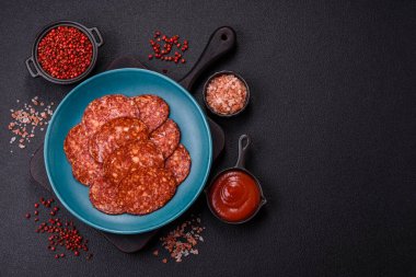 Lezzetli tütsülenmiş sucuklu sosis. Tuz, baharat ve otlarla dilimlenmiş. Koyu beton arka planda.