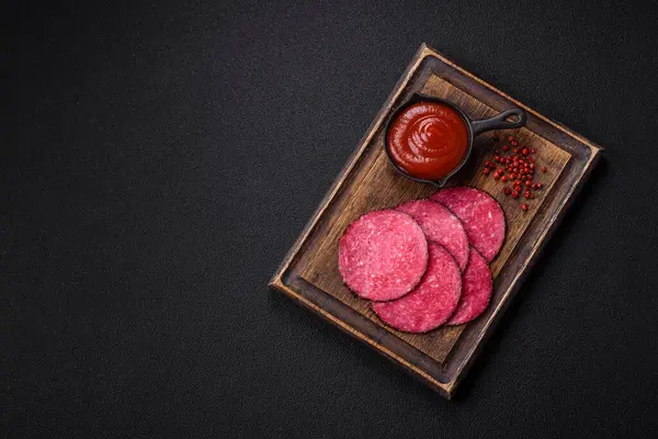 stock image Delicious smoked salami sausage sliced with salt, spices and herbs on a dark concrete background