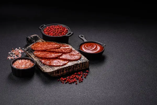 Lezzetli tütsülenmiş sucuklu sosis. Tuz, baharat ve otlarla dilimlenmiş. Koyu beton arka planda.