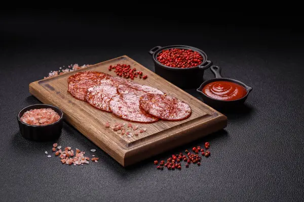 Lezzetli tütsülenmiş sucuklu sosis. Tuz, baharat ve otlarla dilimlenmiş. Koyu beton arka planda.