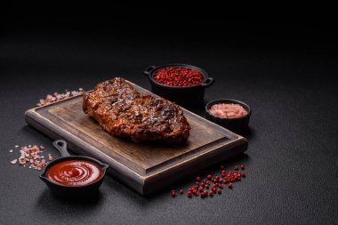 Karanlık bir arka planda taze sulu lezzetli biftek. Baharatlı ve otlu et yemeği.