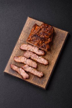 Karanlık bir arka planda taze sulu lezzetli biftek. Baharatlı ve otlu et yemeği.