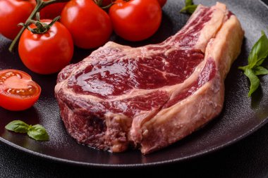 Taze, çiğ biftek, tuz, baharat ve otlar koyu dokulu arka planda.