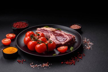 Taze, çiğ biftek, tuz, baharat ve otlar koyu dokulu arka planda.